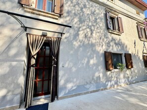 A building facade with a window, a door, and a small window with a plant. - Apartments Ladonia (16296-A3) - Krnica (Pula) (Krnica (Pula))