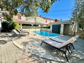 A pool area with lounge chairs, a covered seating area, and a stone building in the background. - Apartments Ladonia (16296-A3) - Krnica (Pula) (Krnica (Pula))