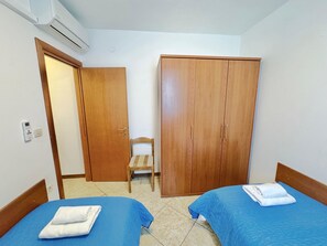 A hotel room with two beds, a wardrobe, a chair, and an air conditioning unit. - Apartments Ladonia (16296-A3) - Krnica (Pula) (Krnica (Pula))
