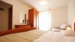 Ein Hotelzimmer mit einem großen Bett, einem Holzschrank, einem Nachttisch mit Lampe und einem Spiegel an der Wand.