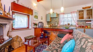 A cozy living room with a fireplace, a sofa, and a dining area with a kitchen in the background. - House Ondina (16469-K1) - Medulin (Medulin)