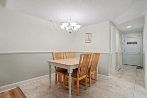 Une salle à manger avec une table et des chaises, un lustre et un tableau encadré au mur.