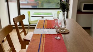 Una mesa de comedor con dos individuales, un florero con flores y dos copas de vino.