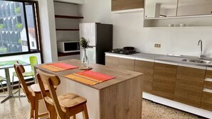 Una cocina moderna con una isla central, sillas de madera, una mesa de comedor y vistas al exterior a través de un ventanal.