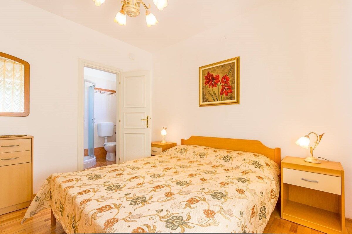 Une chambre à coucher comprenant un lit, une table de chevet, une commode et une porte donnant accès à une salle de bain.
