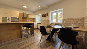 A modern kitchen with wooden flooring, a central island with bar stools, and a dining area with a table and chairs. - Apartments Hodak (16589-A1) - Pula (Pula)