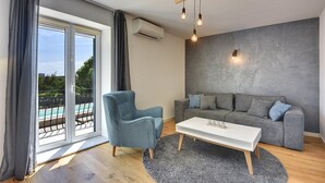 A modern living room with a grey sofa, a blue armchair, and a white coffee table. - Apartments Hodak (16589-A1) - Pula (Pula)
