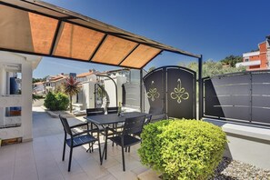 An outdoor patio with a table and chairs, a covered area, and a decorative gate. - Apartments Hodak (16589-A1) - Pula (Pula)