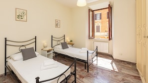 Ein Schlafzimmer mit zwei Betten, einem Fenster und einer Heizung.