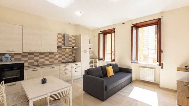 Eine moderne Küche mit Essbereich, einer Couch und einem Fenster mit Jalousien.