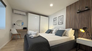 Un dormitorio moderno con cama, mesita de noche, lámpara y un escritorio con silla.