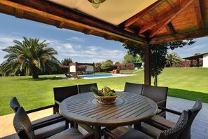 A covered patio with a round table and chairs, a fruit bowl, and a view of a swimming pool and lawn. - Villa Sunny Flowers (16659-K1) - Medulin (Medulin)