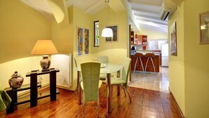 Un comedor con una mesa, sillas, una lámpara y obras de arte en las paredes.