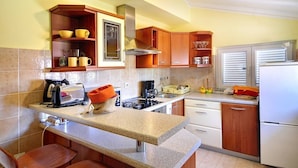 Una cocina con armarios de madera, una encimera, una estufa y un refrigerador.