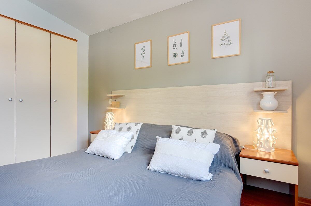 Ein Schlafzimmer mit einem Bett, Nachttischen, einer Nachttischlampe und Wandregalen.