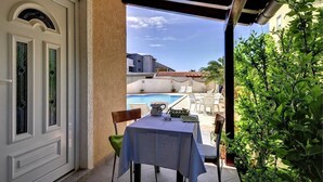 Un patio con tavolo e sedie, una piscina sullo sfondo e vista su edifici.