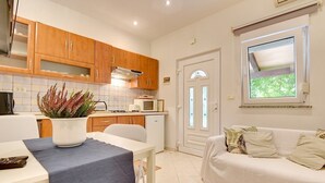Una cucina moderna con mobili in legno, un piano di lavoro bianco e una zona pranzo con tavolo e sedie.