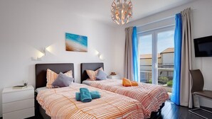 Een moderne hotelkamer met twee bedden, een groot raam met gordijnen, een flatscreen televisie en een schilderij aan de muur.