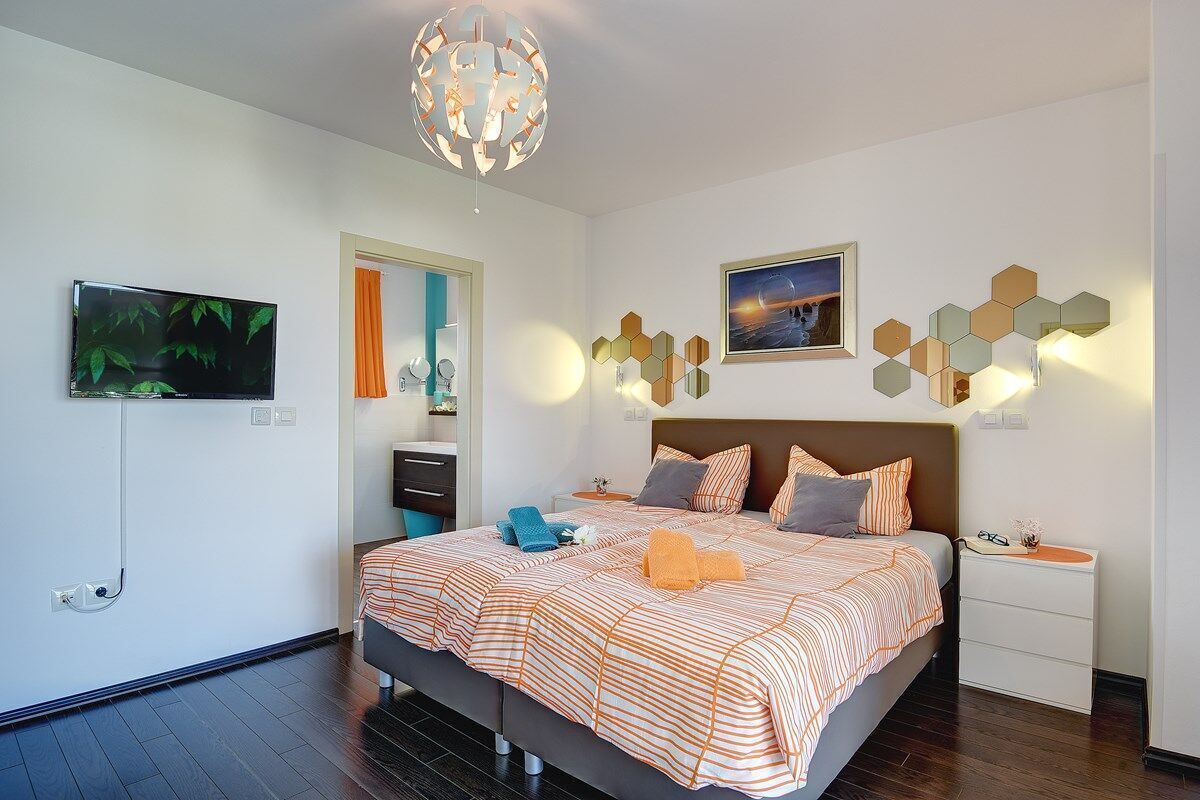 Une chambre moderne avec un grand lit, une télévision et des appliques murales décoratives.