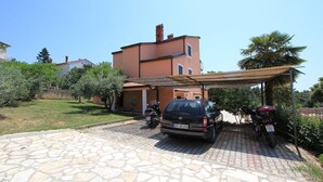 A stone-paved driveway leading to a two-story house with a car and motorcycles parked in the driveway. - Apartments Susy (16851-A3) - Pula (Pula)