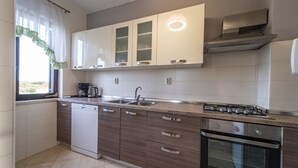 Une cuisine moderne avec des armoires blanches, un four encastré et une cuisinière à gaz.