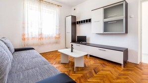 Un espacio habitable compacto con sofá, una mesita y una zona de kitchenette.