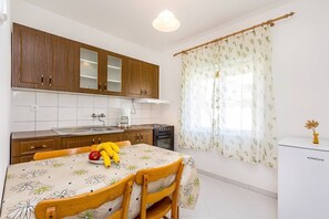 Eine Küche mit Holzausstattung, einem Esstisch mit Blumenmuster und einem Kühlschrank.