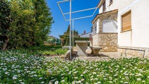 Un patio con un banco de piedra, una estructura metálica y un edificio blanco de fachada de piedra.