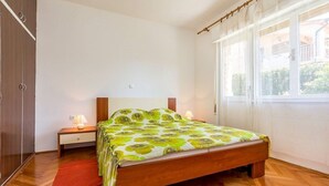 Un dormitorio con cama de madera, una mesita de noche, una lámpara y una ventana con cortinas.