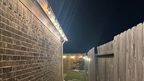 A narrow pathway with stepping stones leading to a wooden fence and a brick wall. - Clean & Calm 3BR Home Near Houston Premium Outlets (Cypress)