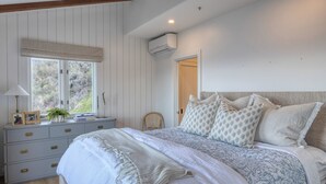 Un dormitorio con cama, cómoda, ventana y equipo de aire acondicionado.