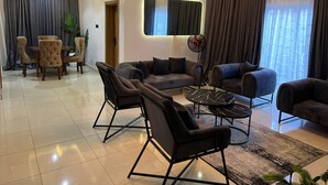 Un salon moderne comprenant un canapé, des fauteuils, une table basse et un coin repas avec une table et des chaises.