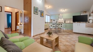 Un salon moderne avec des canapés verts, une table basse en bois et un téléviseur en arrière-plan.