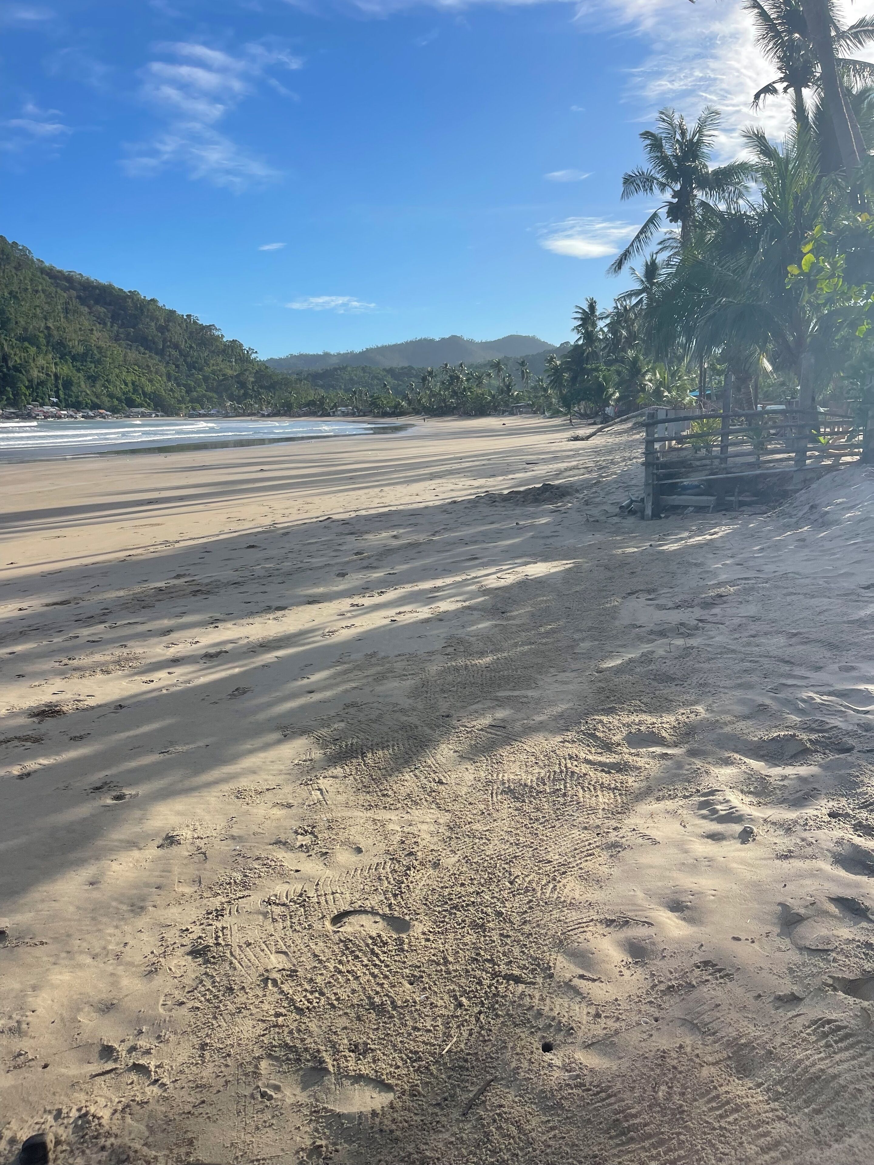 Una playa con huellas y una valla de madera.