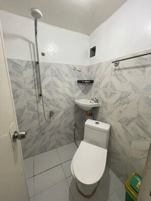 Chuveiro, toalhas de banho, sabonete, papel higiênico