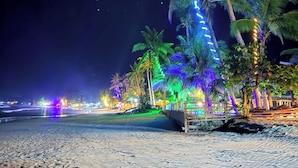 A beach with palm trees and colorful lights.