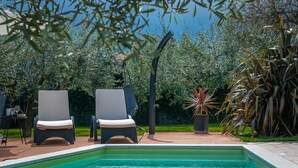 A swimming pool with two lounge chairs and a table with drinks, surrounded by greenery and a pergola. - Villa Laura (16946-K1) - Krnica (Pula) (Krnica (Pula))