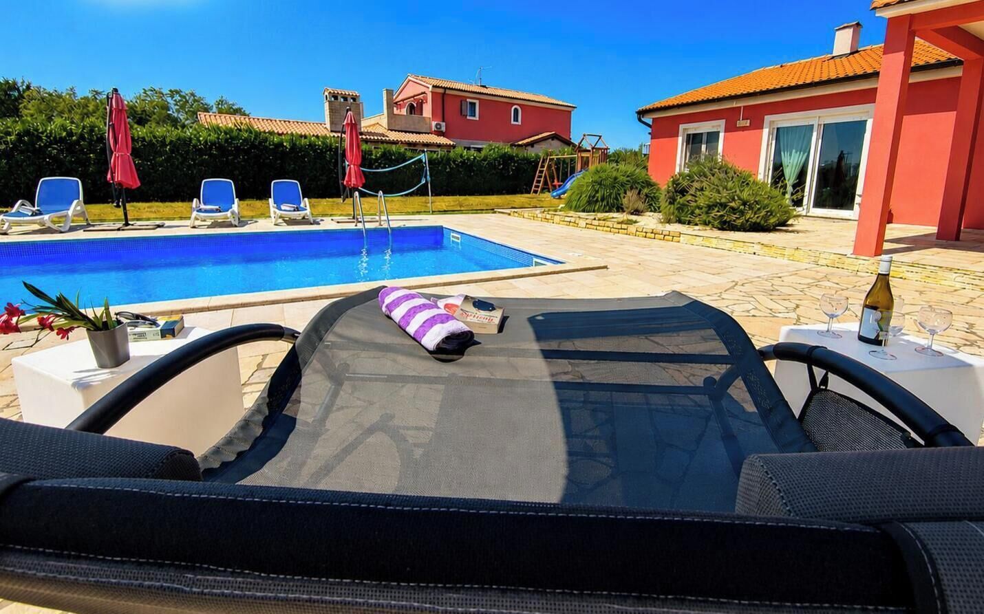 A poolside area with lounge chairs, a pool, and a building in the background.