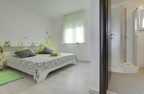 A bedroom with a bed, a window with curtains, a green rug, and a shower area. - Villa Kata (73534-K1) - Krnica (Pula) (Krnica (Pula))