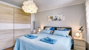 Et soveværelse med seng, sengeborde, et billede på væggen og en dekorativ lampe.