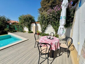 Eine Terrasse mit Pool, Sitzgelegenheiten im Freien und einem Tisch mit Tischdecke.