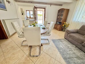 A dining area with a round table, white chairs, and a cabinet with glass doors. - Apartments Barat (73588-A1) - Zminj (Zminj)
