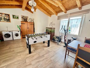 A room with a foosball table, washing machines, exercise equipment, and a window with curtains. - Apartments Barat (73588-A2) - Zminj (Zminj)