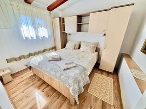 A bedroom with a bed, a nightstand, a wardrobe, and a window with curtains. - Apartments Barat (73588-A2) - Zminj (Zminj)