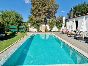 A rectangular swimming pool with a tiled edge, surrounded by a wooden deck. There are lounge chairs with umbrellas and a table with chairs on the deck. - Apartments Barat (73588-A2) - Zminj (Zminj)