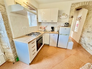 A compact kitchen with white cabinets, a gas stove, a dishwasher, and a refrigerator. - Apartments Barat (73588-A2) - Zminj (Zminj)