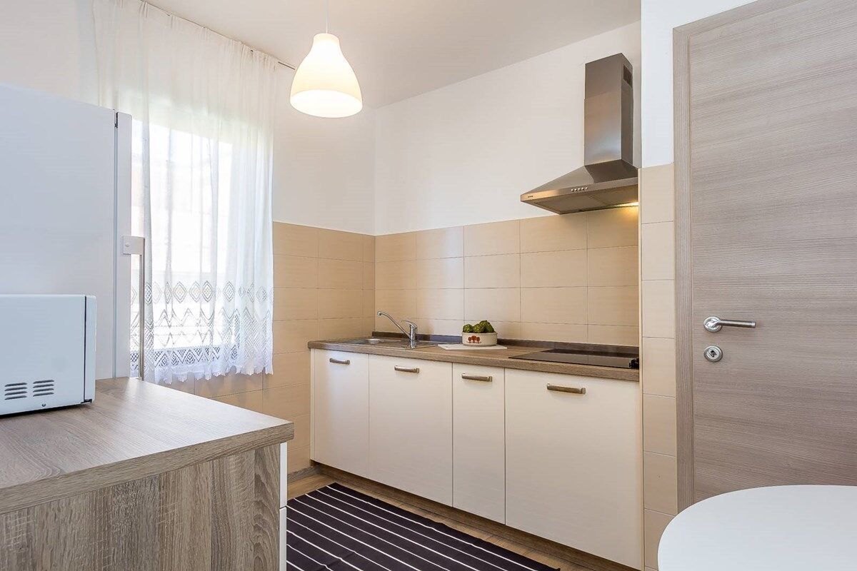 A modern kitchen with a built-in oven, a sink, and a stainless steel range hood.