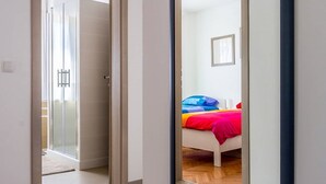 Een moderne slaapkamer met een bed, kleurrijke beddengoed en een glazen douchedeur.