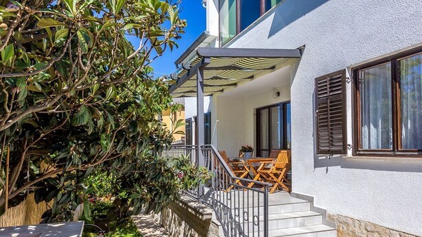 Een tweelaags huis met balkon, buiten zitplaatsen en een pad van stenen.