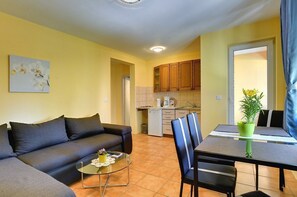 A compact living space with a sofa, a dining table with chairs, a small kitchen area, and a potted plant. - Apartments Puntica (73597-A2) - Liznjan (Liznjan)